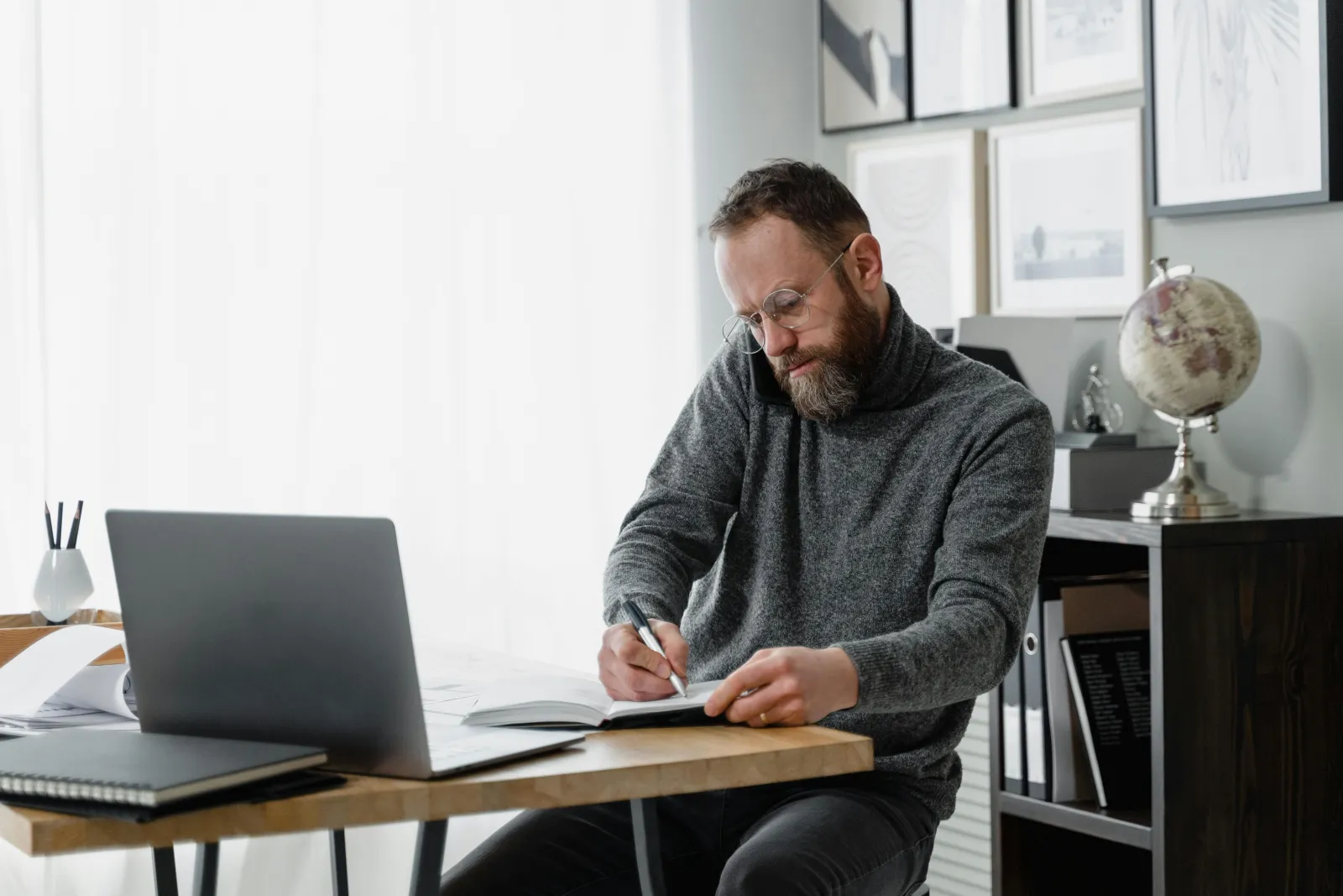 Mann går gjennom papirer og en laptop ved et hjemmekontor