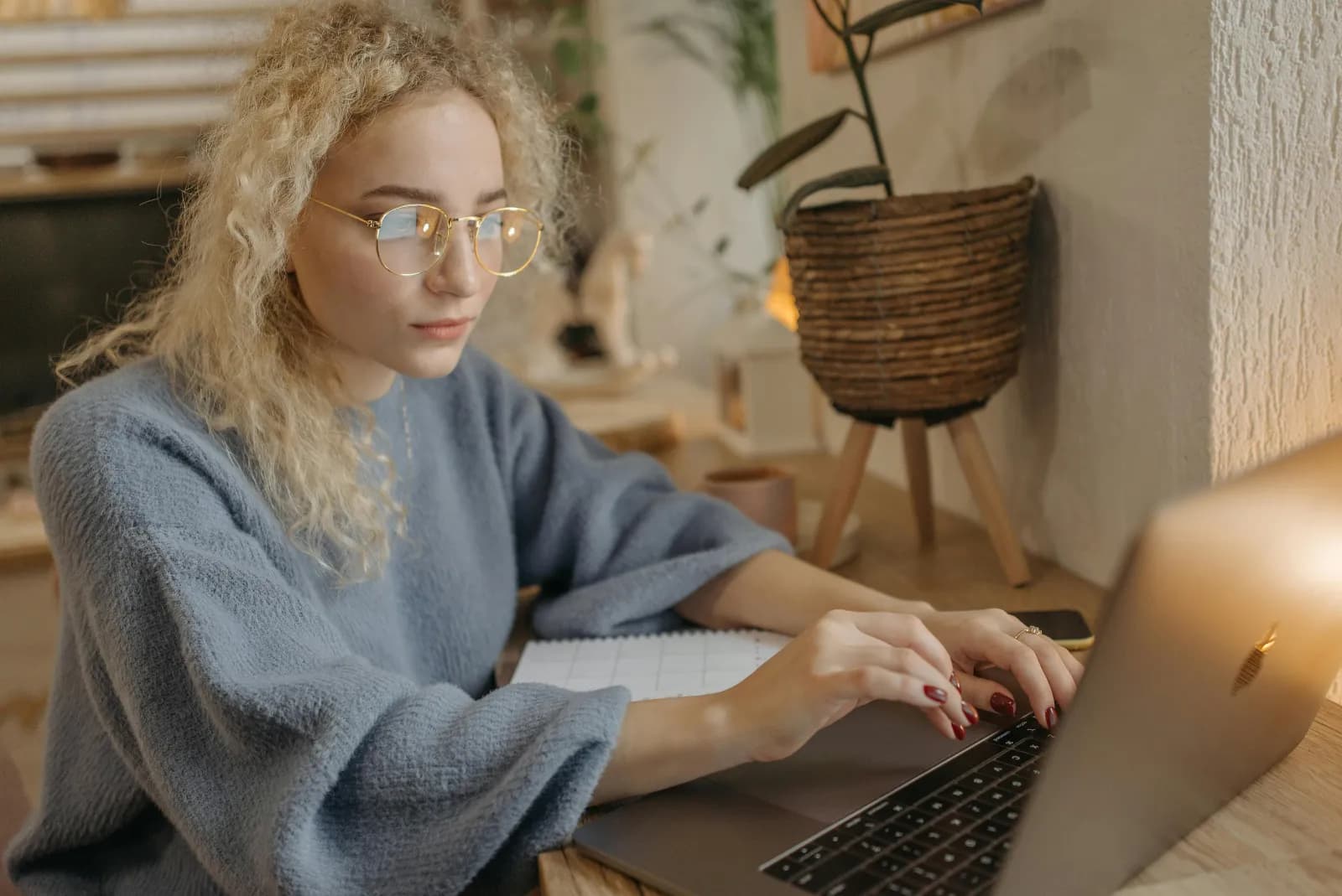 Kvinne med briller fordypet i en laptop på et koselig hjemmekontor