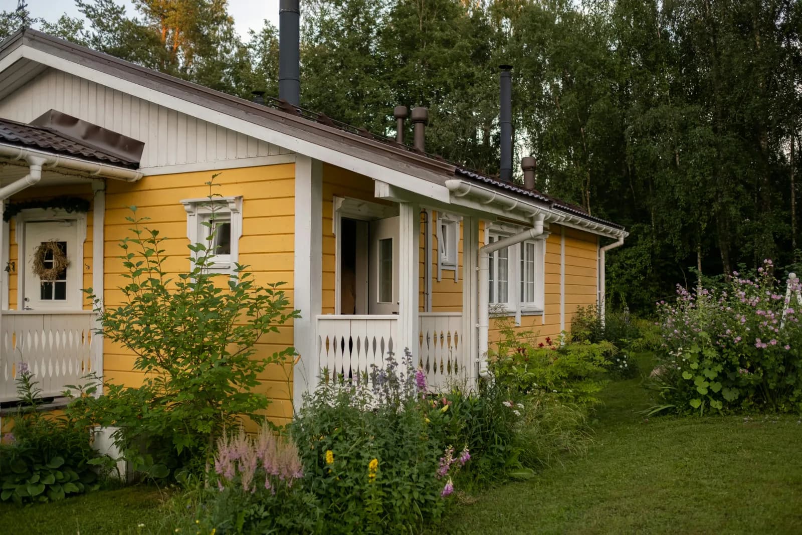 Gul hytte med sommerblomster på landet en fin dag