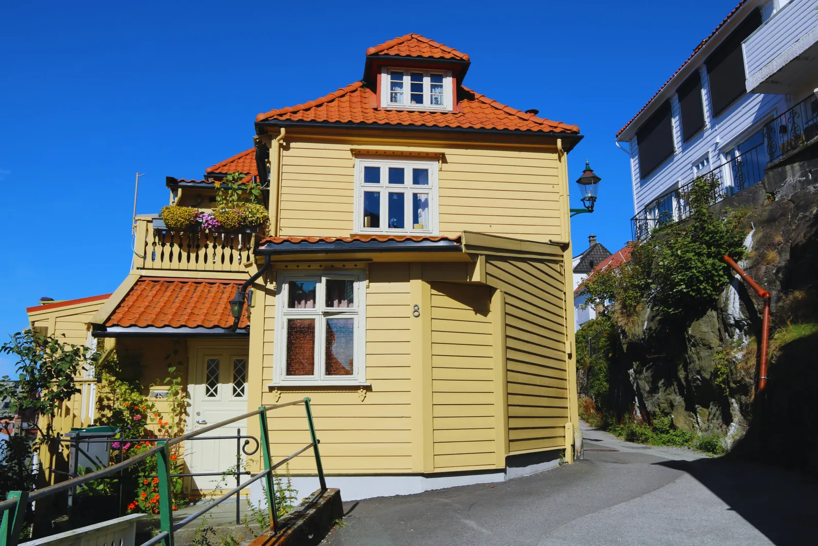 Gult trehus med rødt tak i Bergen en solrik dag